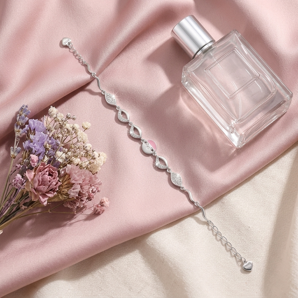 Pink Enamel & Pave Leaf Silver Bracelet laid flat on blush pink satin fabric highlighting the adjustable chain and dainty heart clasp