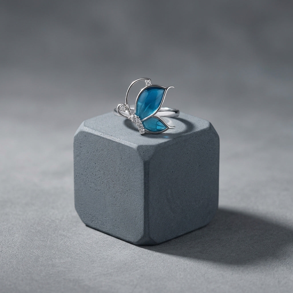 Blue butterfly silver ring displayed on a gray stone block