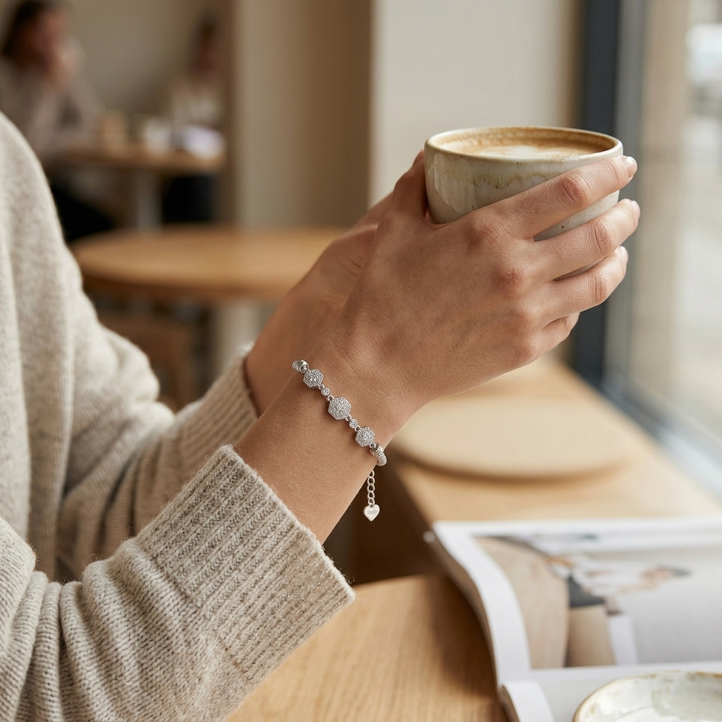 Close up of a woman wearing the Diamond Whisper Silver Bracelet while holding a ceramic coffee cup in a cafe