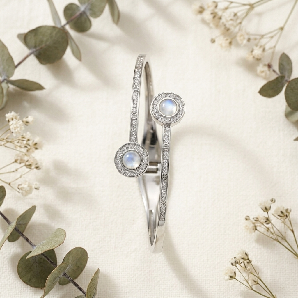 Close-up of a Dual Circle Silver Open Kada with sparkling crystals and iridescent center stones, surrounded by baby's breath and eucalyptus leaves. 
