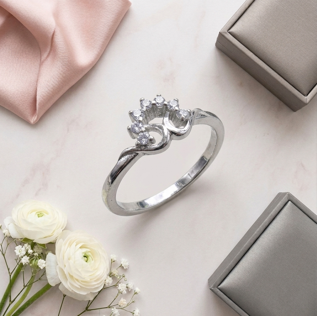Flat lay presentation of the Flower Diamond Silver Ring resting on a marble surface alongside white ranunculus flowers, pink silk, and grey jewelry boxes.