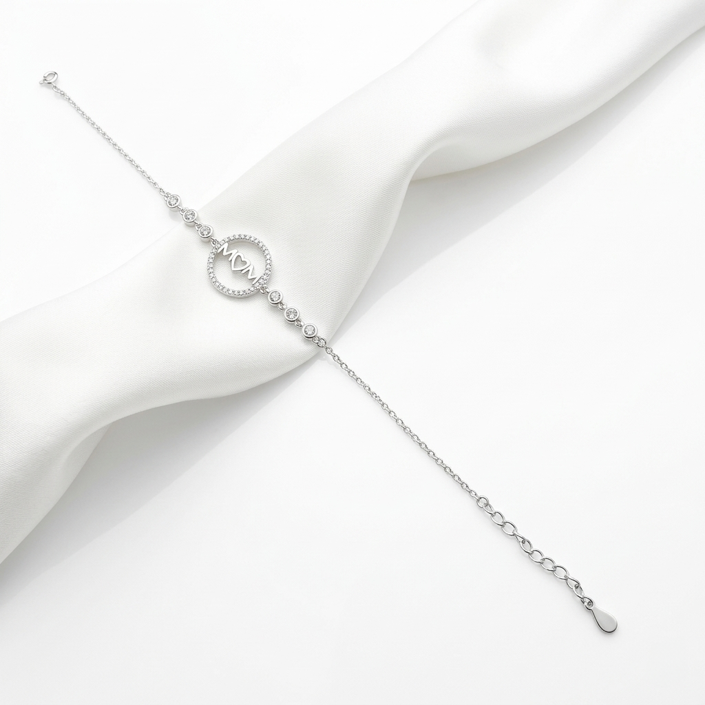 Full view of the silver "MOM" bracelet, showing the side stones and adjustable chain on white fabric.