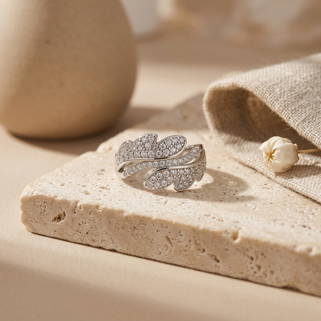 Close-up of the Leaf design Silver Ring displayed on a textured beige stone next to linen fabric.