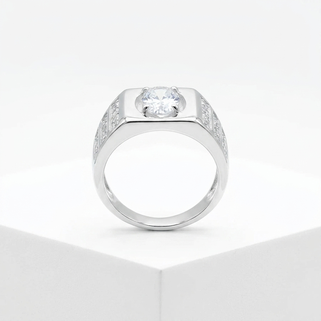 Studio macro shot of a Men’s Silver Stone Ring on a white display block, detailing the round center stone and channel-set side stones.