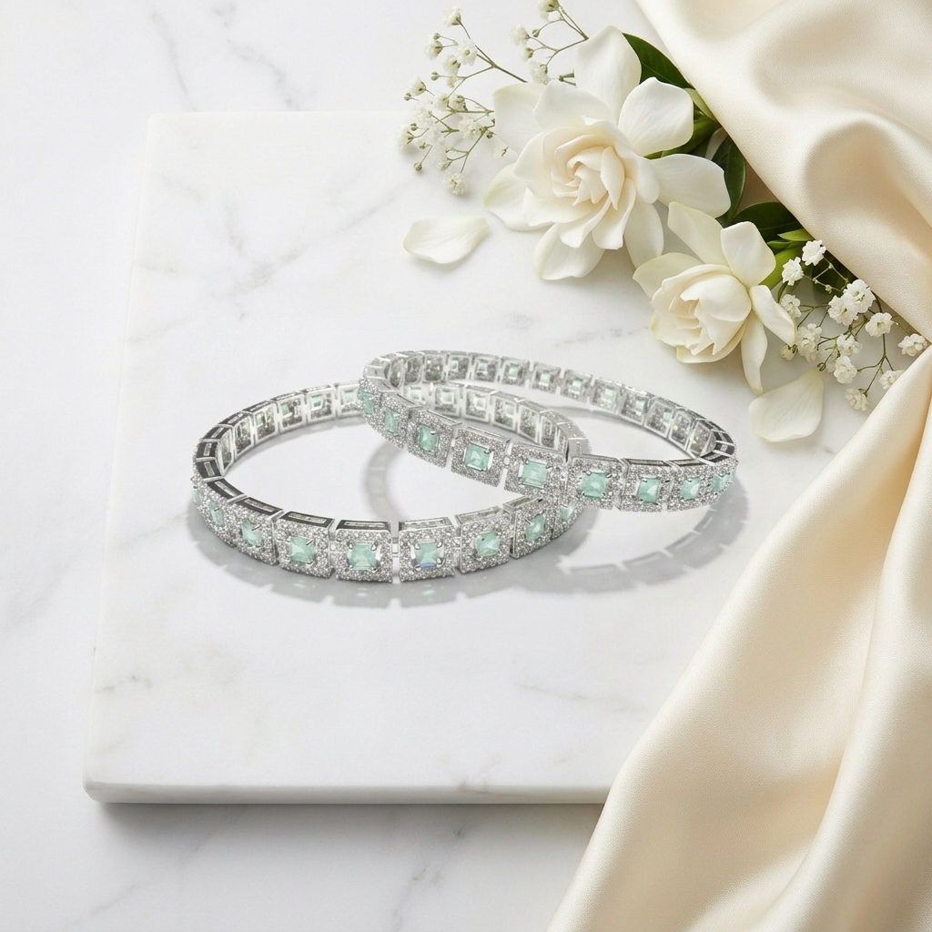 Pair of Mint Green Stone Silver bangles resting elegantly on a white marble slab next to white gardenia flowers and cream satin fabric.