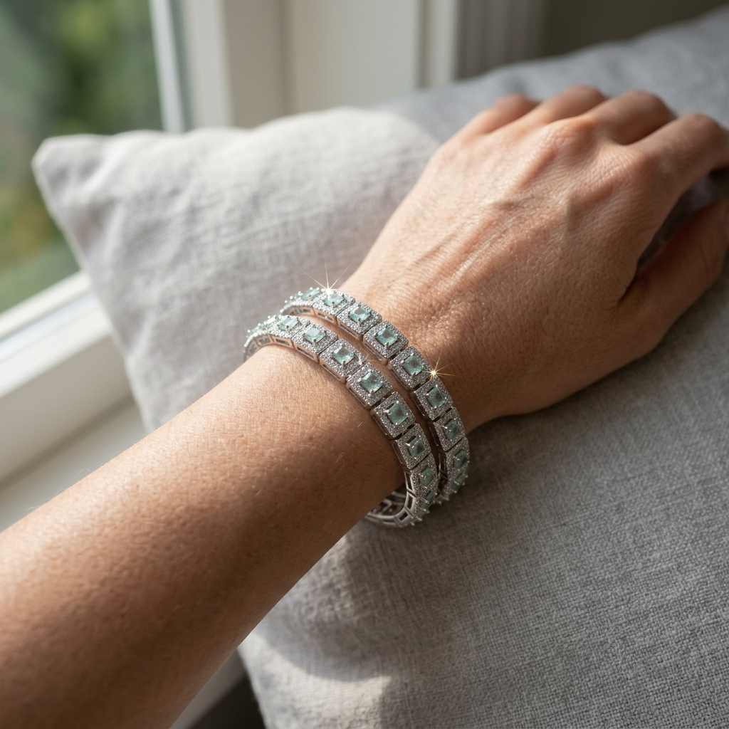 Close-up of a woman's wrist adorned with sparkling Mint Green Stone Silver bangles, resting on a soft grey textured cushion by a sunlit window.