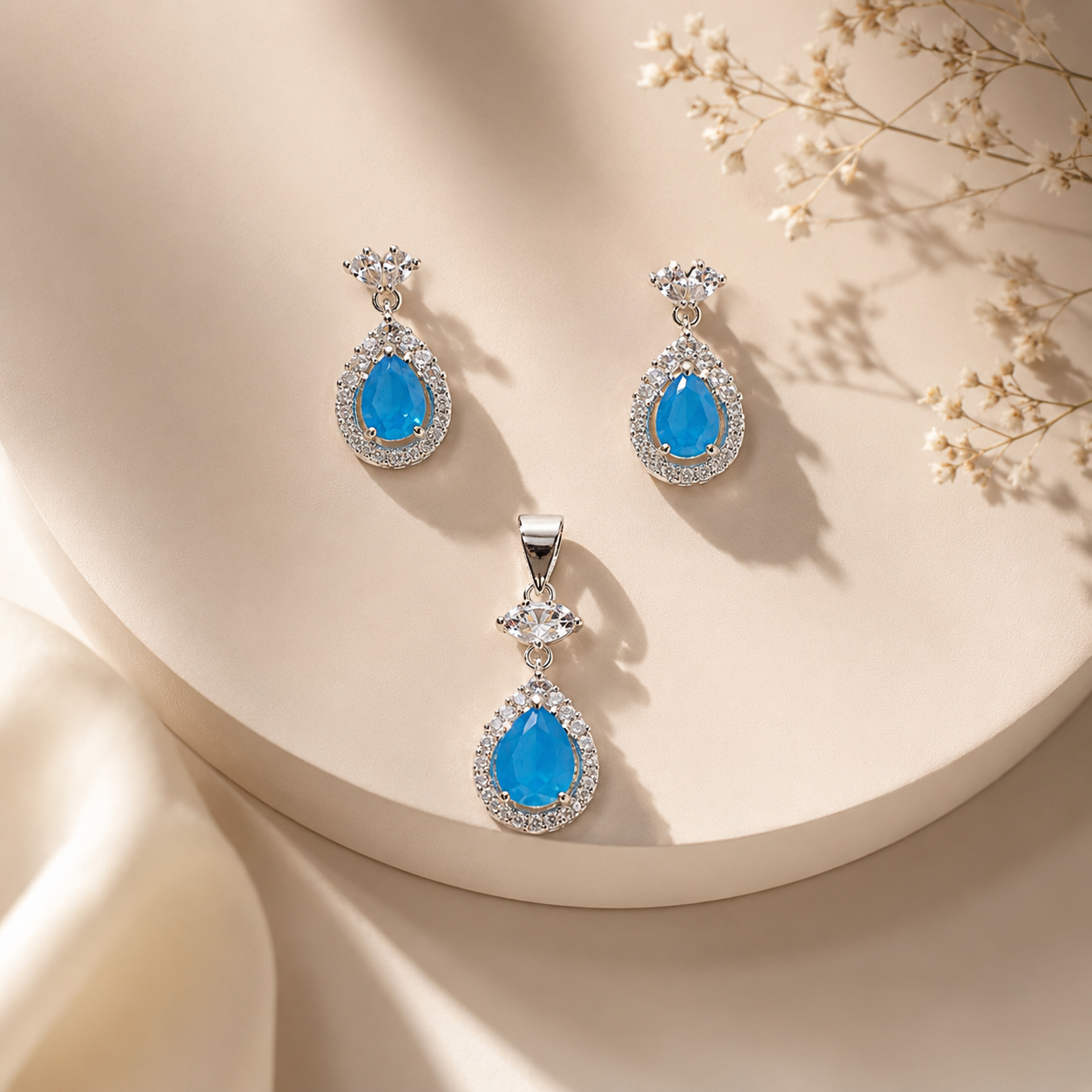 Top-down view of the silver jewelry set featuring vibrant blue teardrop stones with clear crystal halos