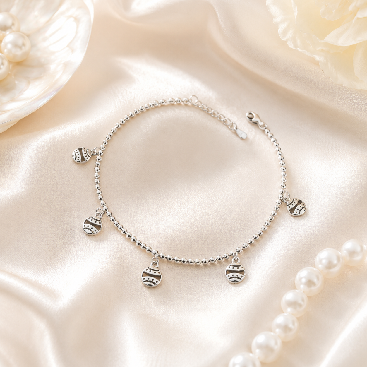 Full flat lay view of the silver beaded ball chain bracelet with ethnic bohemian charms on a solid background