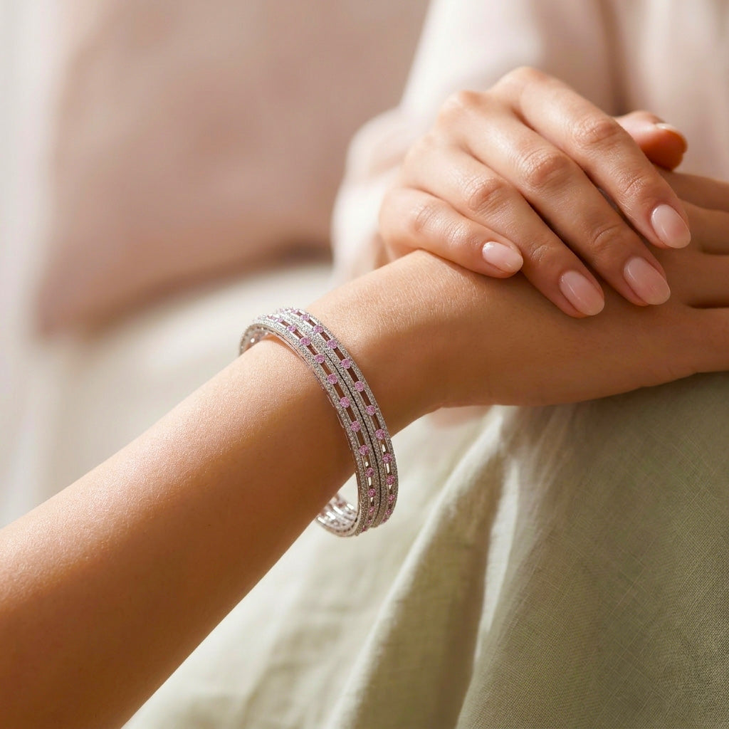 Close-up of a hand wearing a silver bangle with pink stones