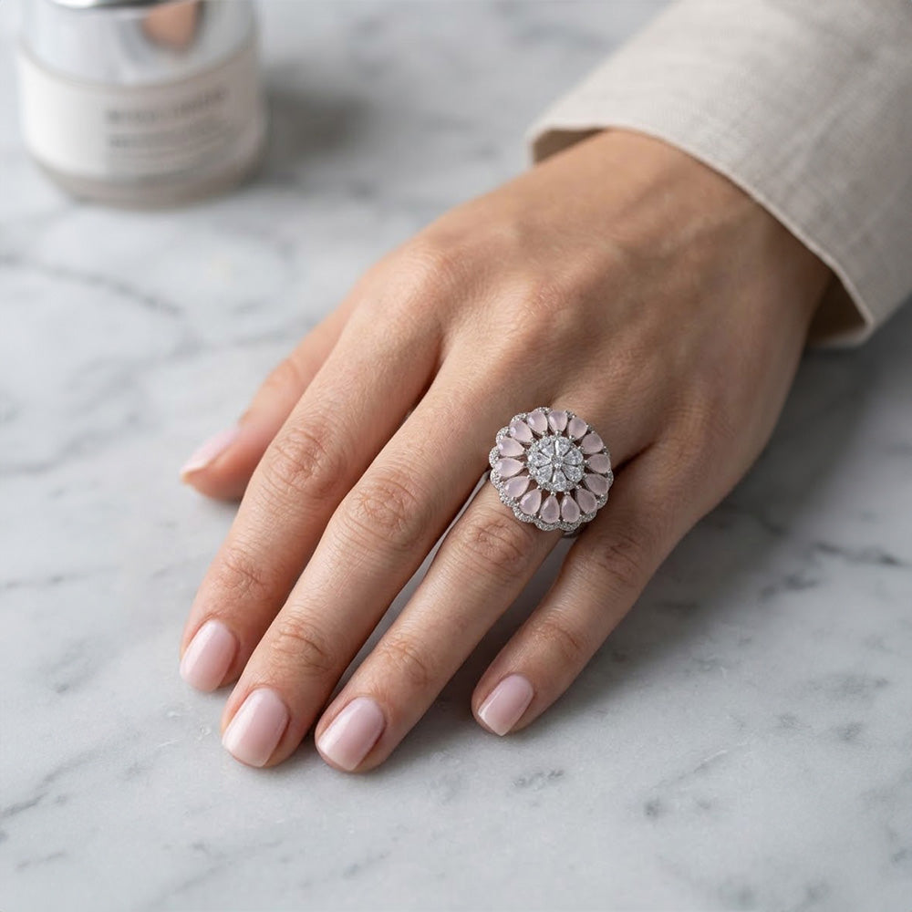 Woman's hand wearing a large floral 925 sterling silver ring with pink stone teardrops