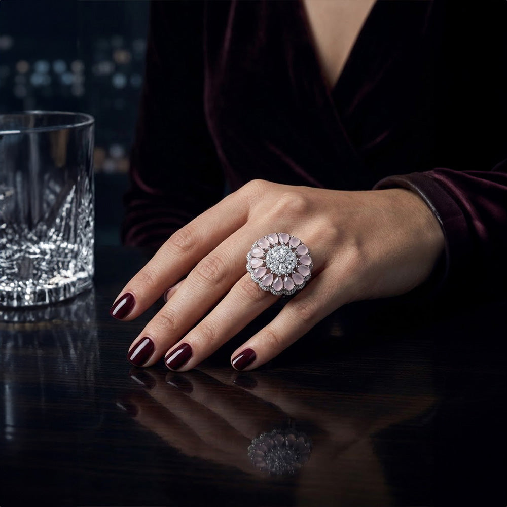 Glamorous evening party look featuring a cocktail silver ring with pink stone worn by a woman with dark maroon nails.