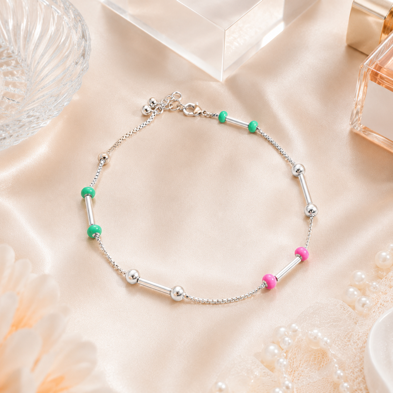 Close up of the adjustable lobster clasp and dangling silver spheres on the pink and green bead anklet.