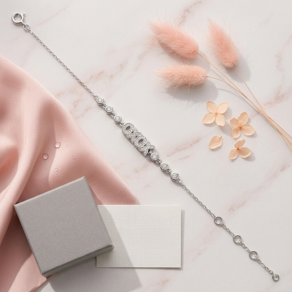 Flat lay of the Raksha Sutra Owl Silver Bracelet next to a grey jewelry box, pink silk fabric, and dried pink flowers on a marble surface.
