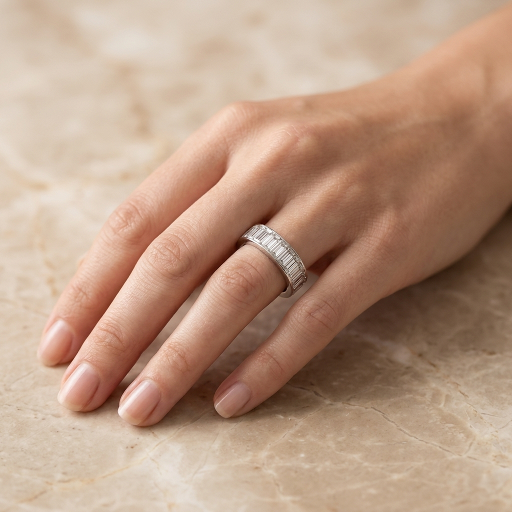 Woman's hand resting on a beige marble surface wearing the Silver Baguette Cut Eternity Ring on her ring finger.