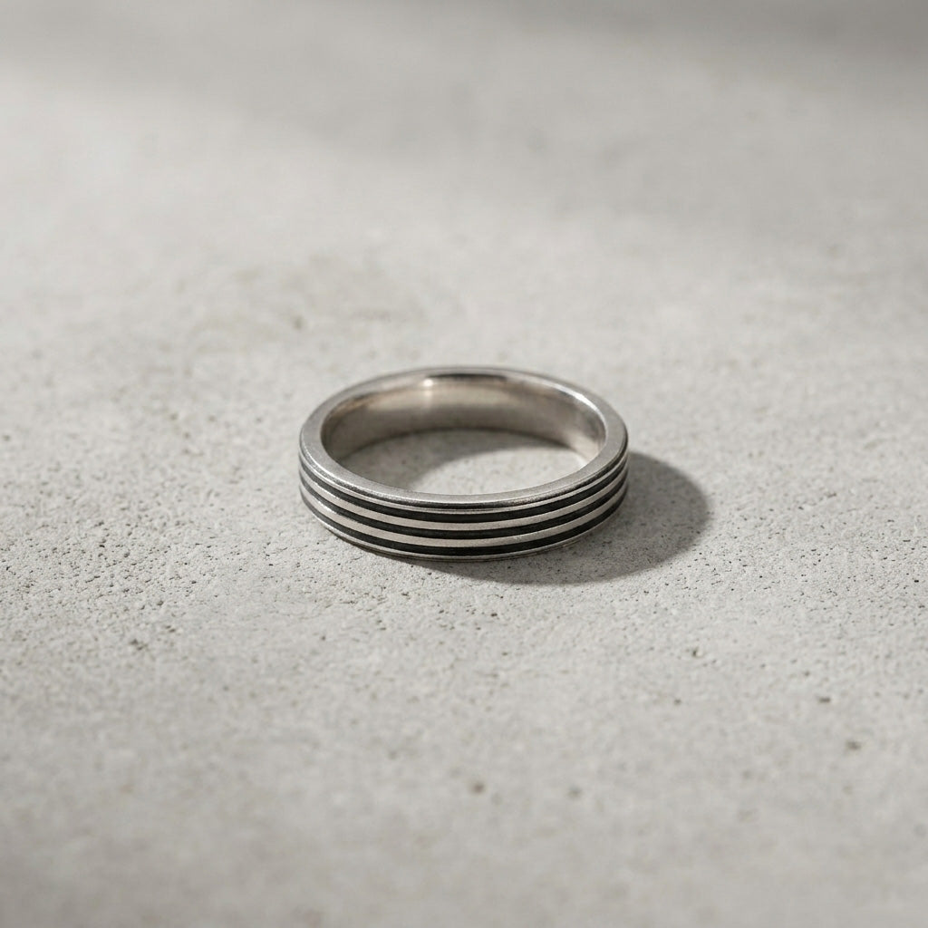 A detailed macro shot of the Three Grooved Silver Ring showcasing the ring's flat pipe-cut profile and industrial design