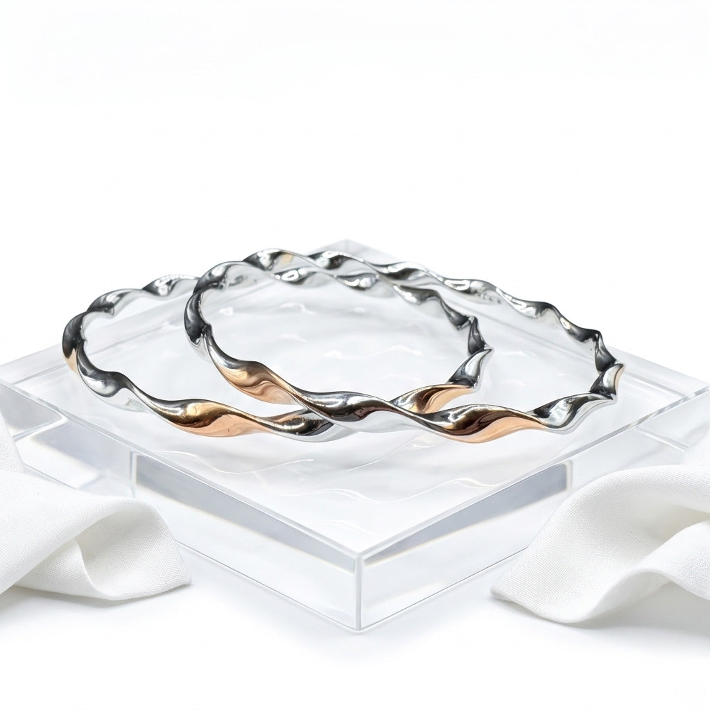 The Silver Twisted Bangle Set resting on a clear, ridged acrylic display stand.