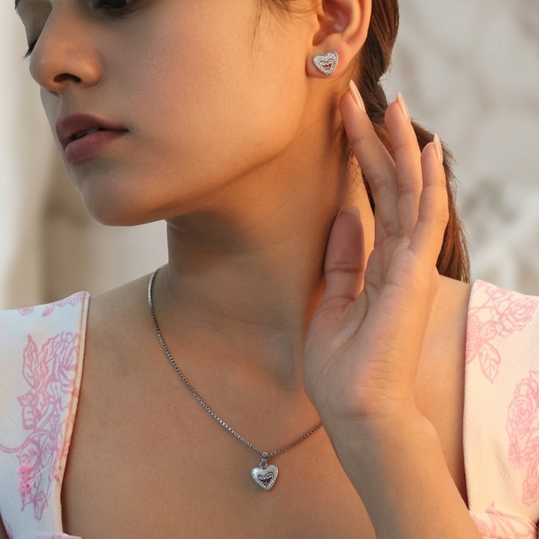 Silver stud earrings with a double heart design and sparkling stones against a white background.