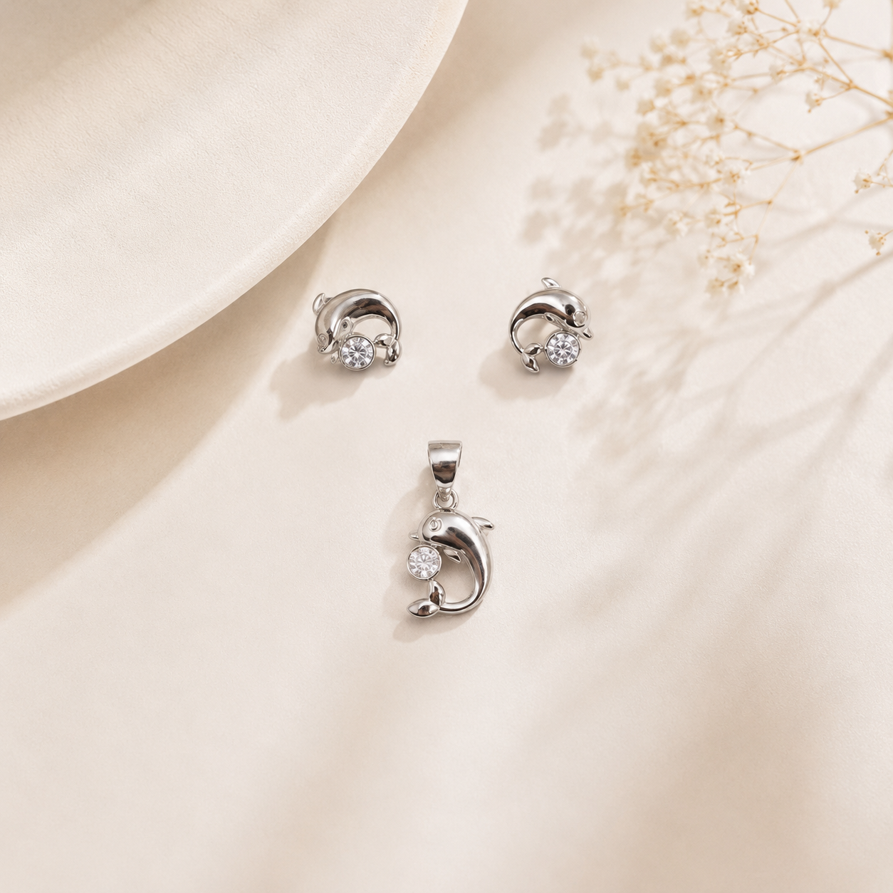 Close-up of the sterling silver dolphin pendant with a prominent crystal resting beside matching earrings