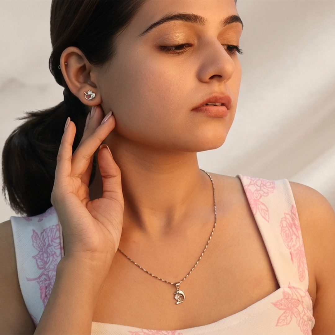 Marine-themed silver jewelry set with leaping dolphin design and delicate white floral decor in the background
