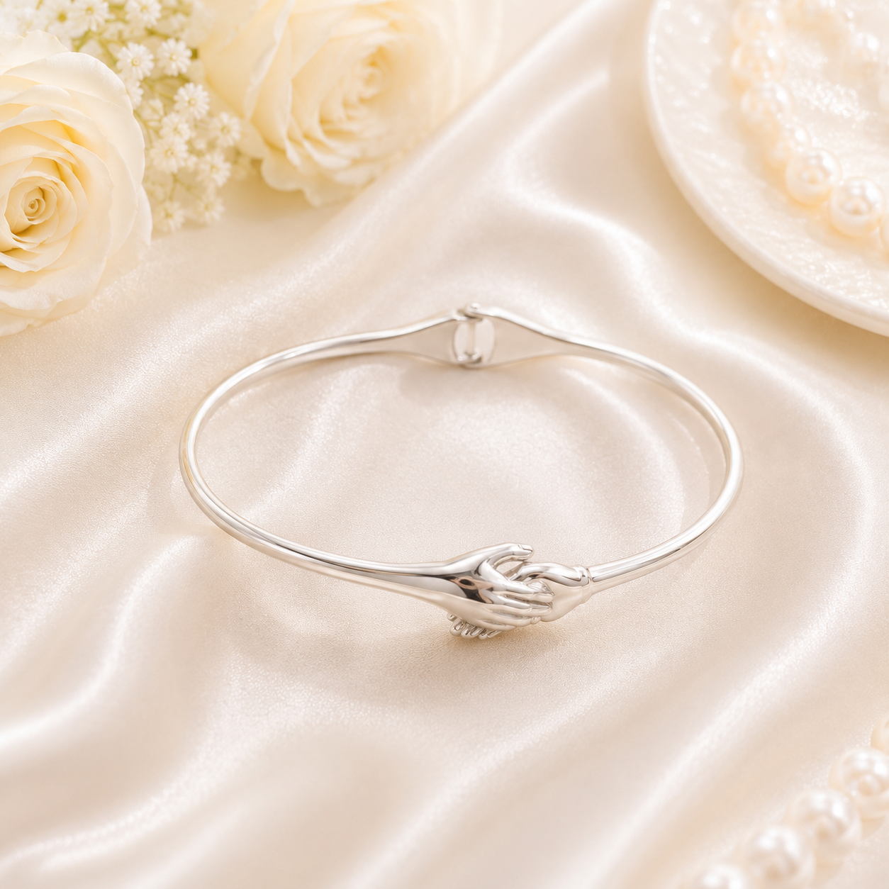 Close-up of the sculpted hands holding each other on the silver promise bracelet.