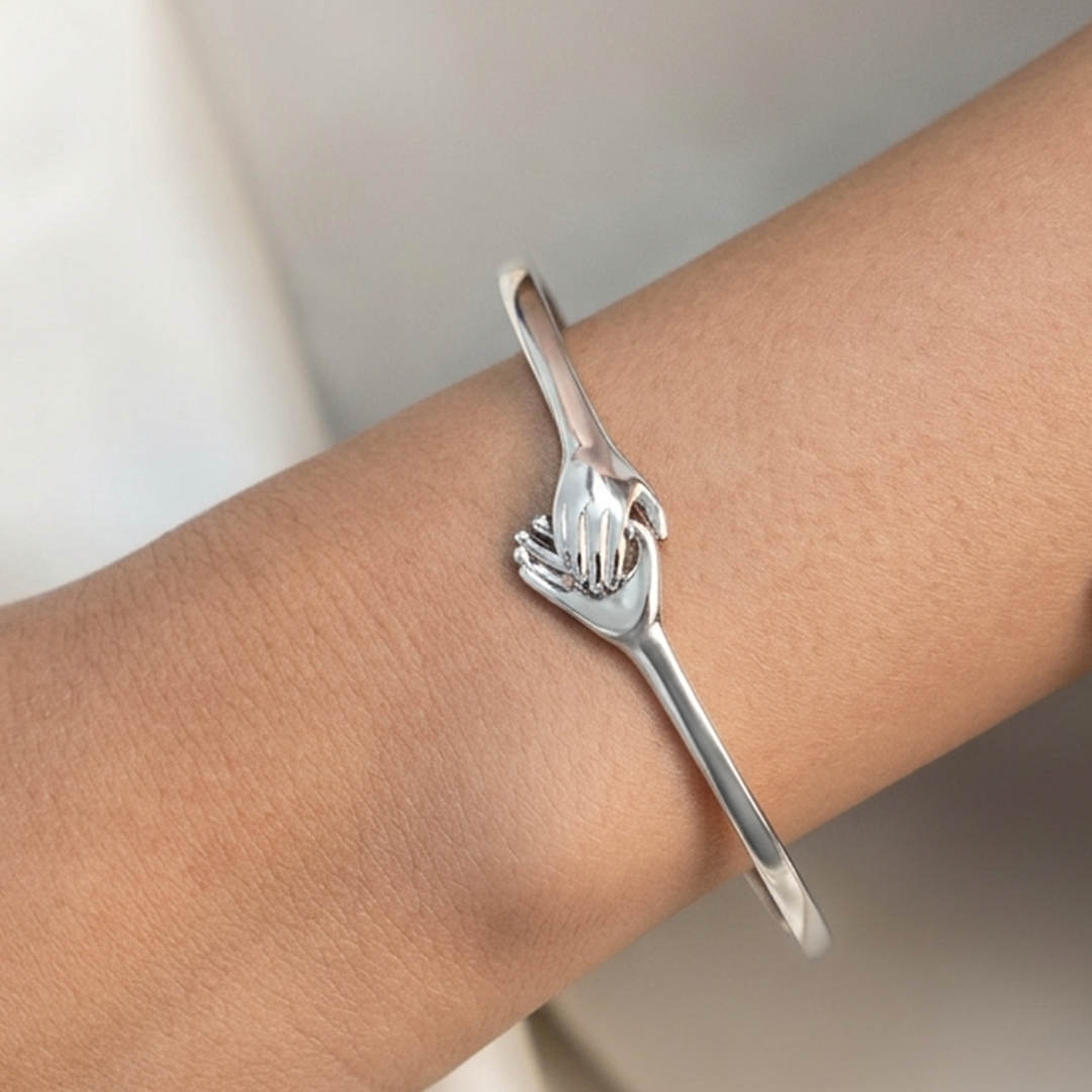 Rigid sterling silver kada with a concealed back hinge and hand-clasp motif