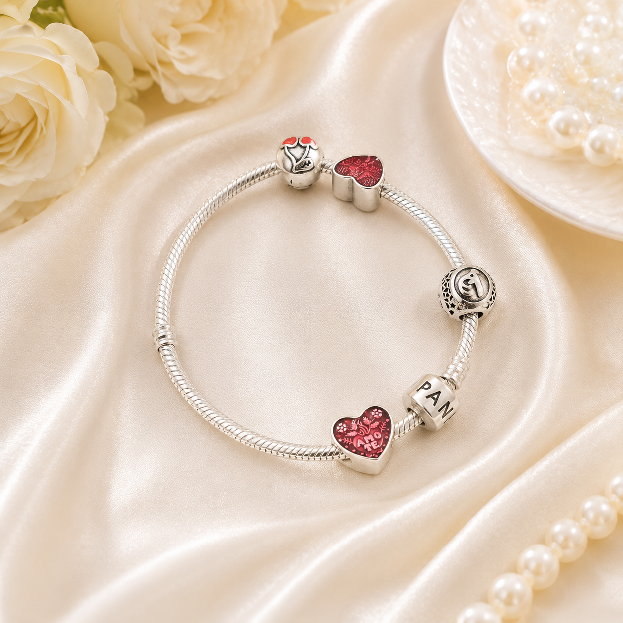 Close-up view of a silver charm bracelet with vibrant red heart accents and textured spacer beads.