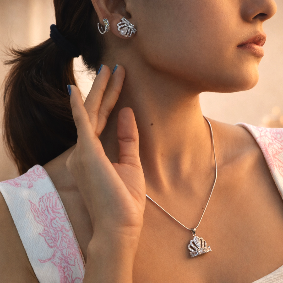 Woman wearing a Sterling Silver Sparkling Crown Pendant necklace with matching pearl-accented crown earrings.