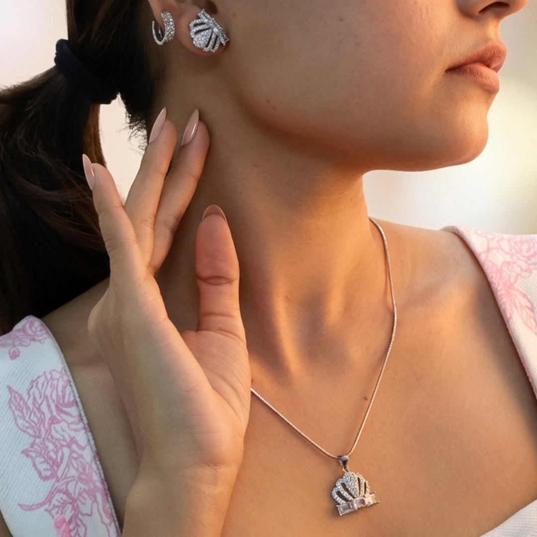 Close-up of a silver crown pendant embedded with cubic zirconia on a smooth snake chain.
