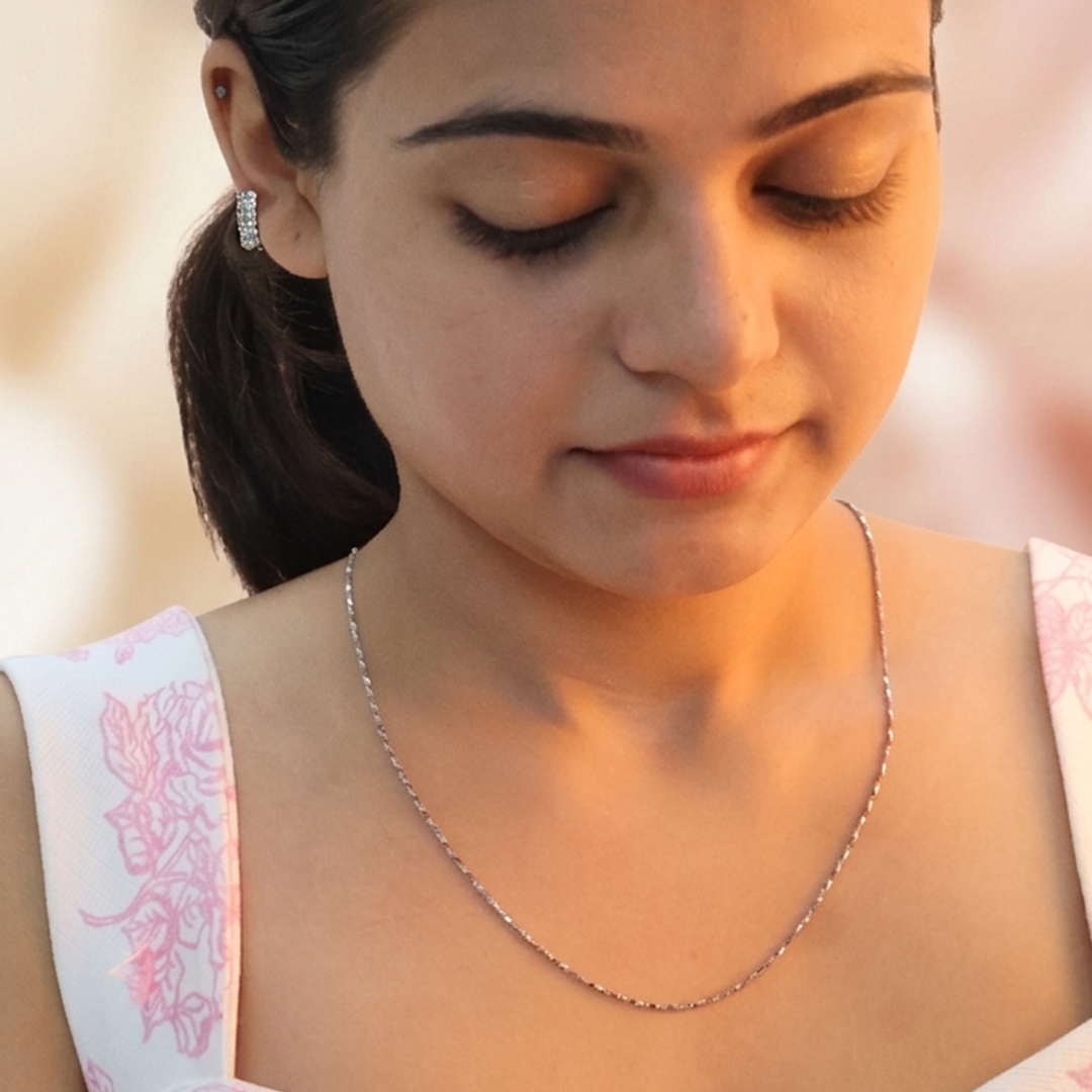 Woman wearing a delicate sterling silver twisted Singapore chain necklace on her collarbone