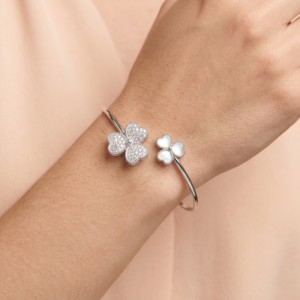 Woman wearing a silver-tone Triple Heart Open Kada featuring pave stones and mother of pearl elements on her wrist. 