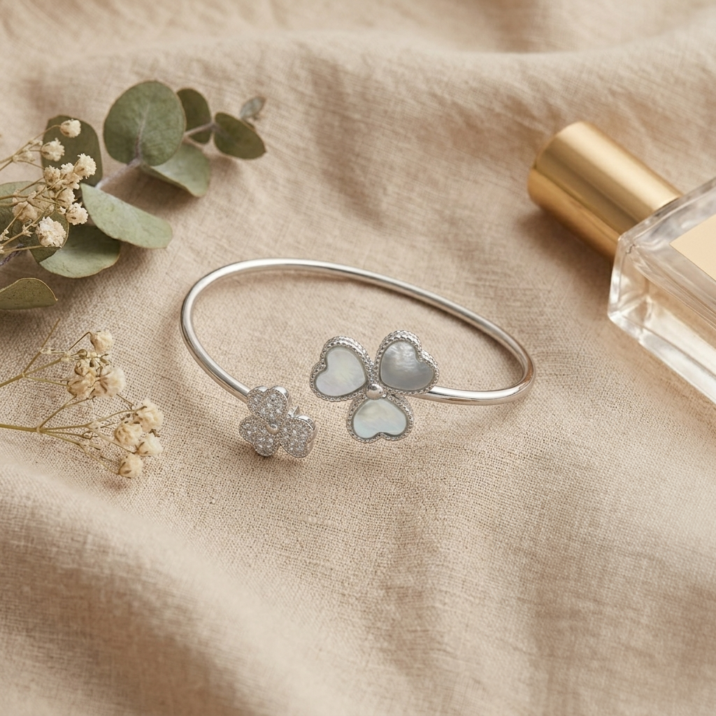 Triple Heart Open Kada styled on a beige fabric next to baby's breath flowers and a glass perfume bottle.