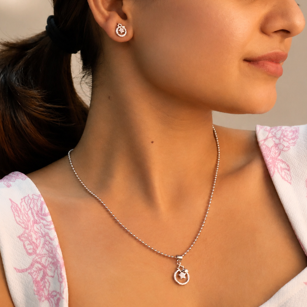 Matching silver stud earrings and pendant with sparkling star designs isolated on whit