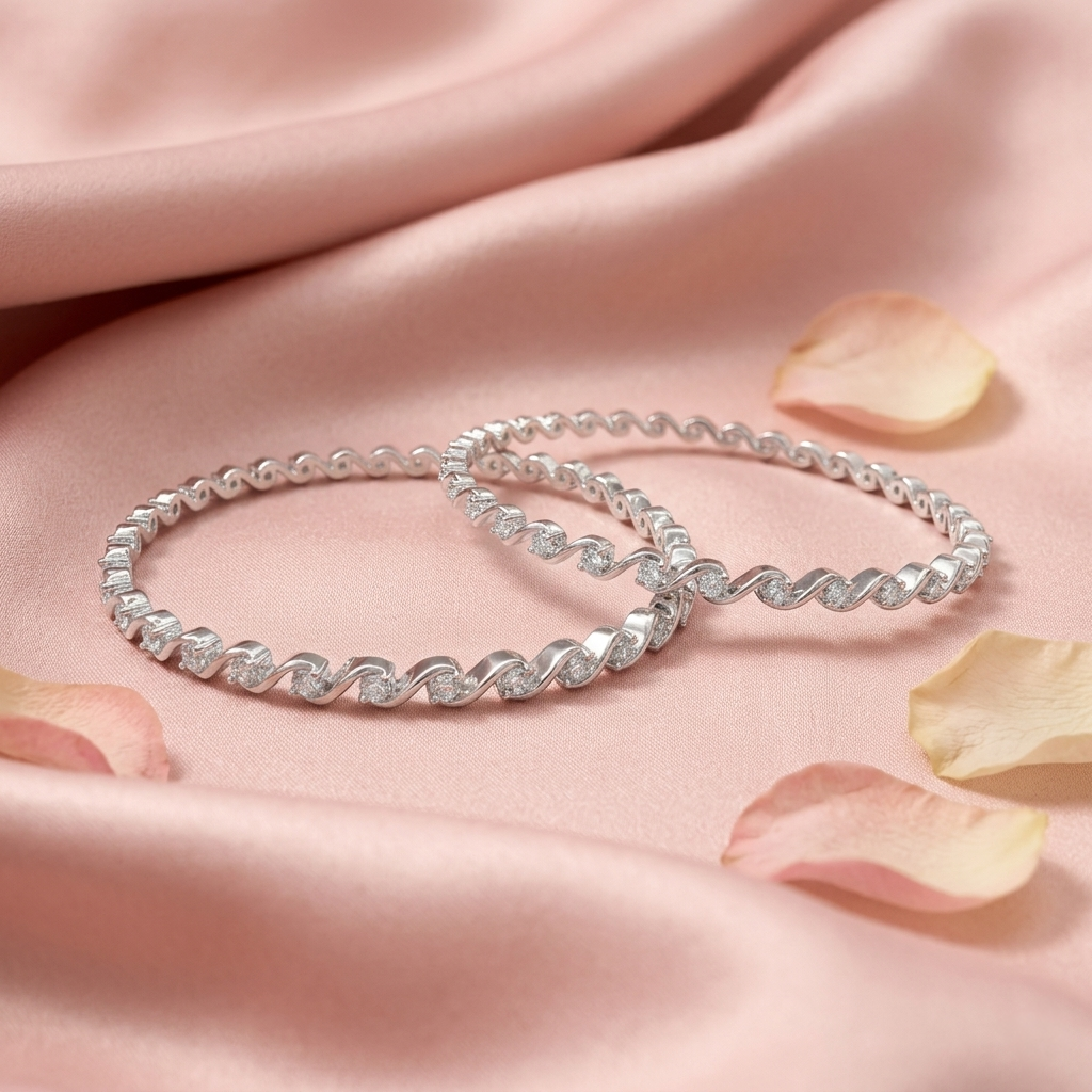 Twisted Wave Silver Bangle Pair resting on pink satin with rose petals