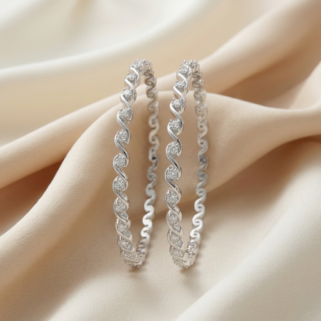 Two Twisted Wave Silver Bangles standing upright on cream-colored fabric