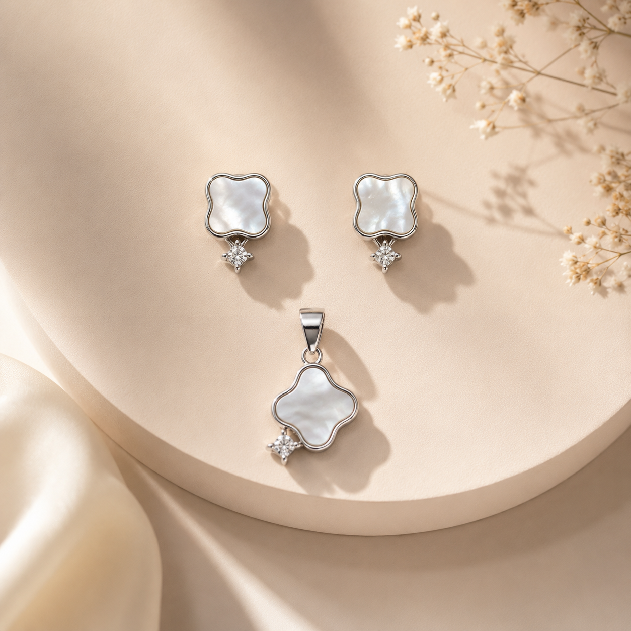 Close up of silver pendant and earrings featuring a four leaf mother of pearl design and small accent stone
