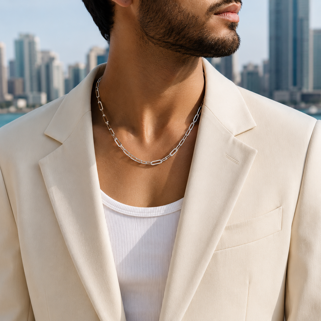 A man wearing the Bold Silver Paperclip Link Statement Chain layered over a white ribbed tank top and styled with a cream blazer.
