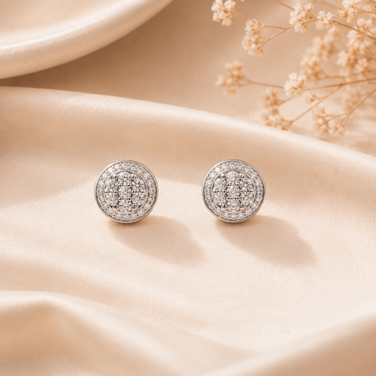 Pair of Brilliant Round Halo Silver Stud Earrings resting gracefully on a soft beige silk fabric