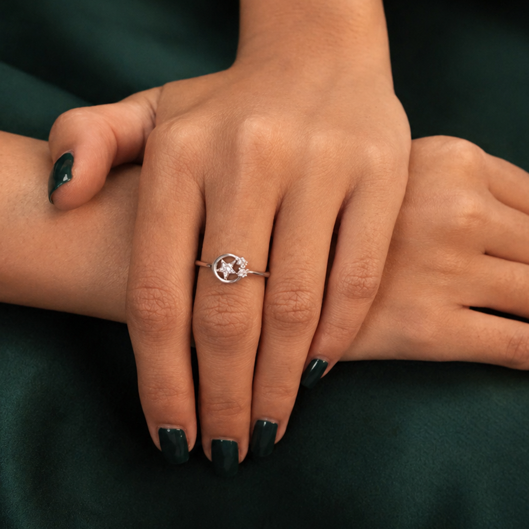 Close-up of a woman's hands with dark green nail polish wearing the Celestial Star Silver Diamond Ring against a deep green velvet background