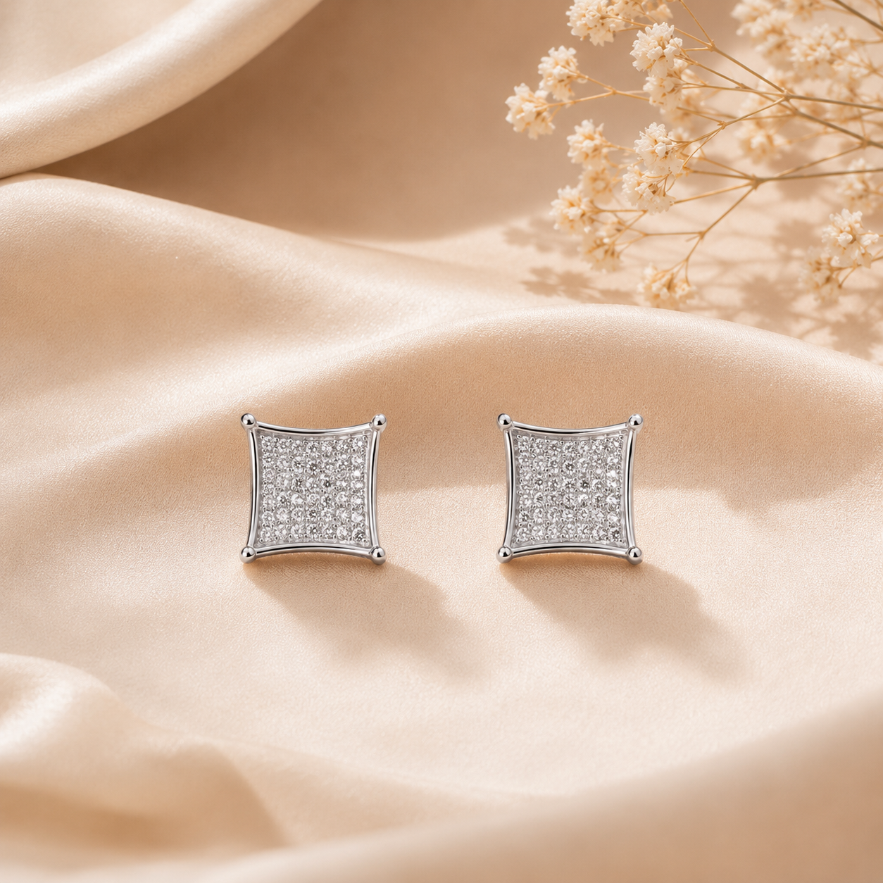 Close up of Concave Square Pave Silver Stud Earrings with pave stones resting on folded silk fabric