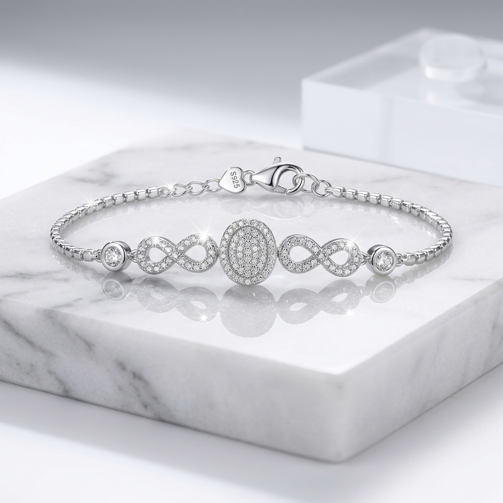 A macro studio shot of the Diamond Look Infinity Silver Bracelet lying flat on white marble, highlighting the sparkling micro-pavé oval centerpiece, infinity loops, and S925 stamped heart clasp