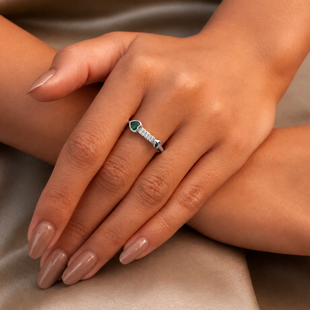 Lifestyle shot of the Emerald Heart Pave Sterling Silver Ring worn on a woman's hand, resting gracefully on a satin dress.