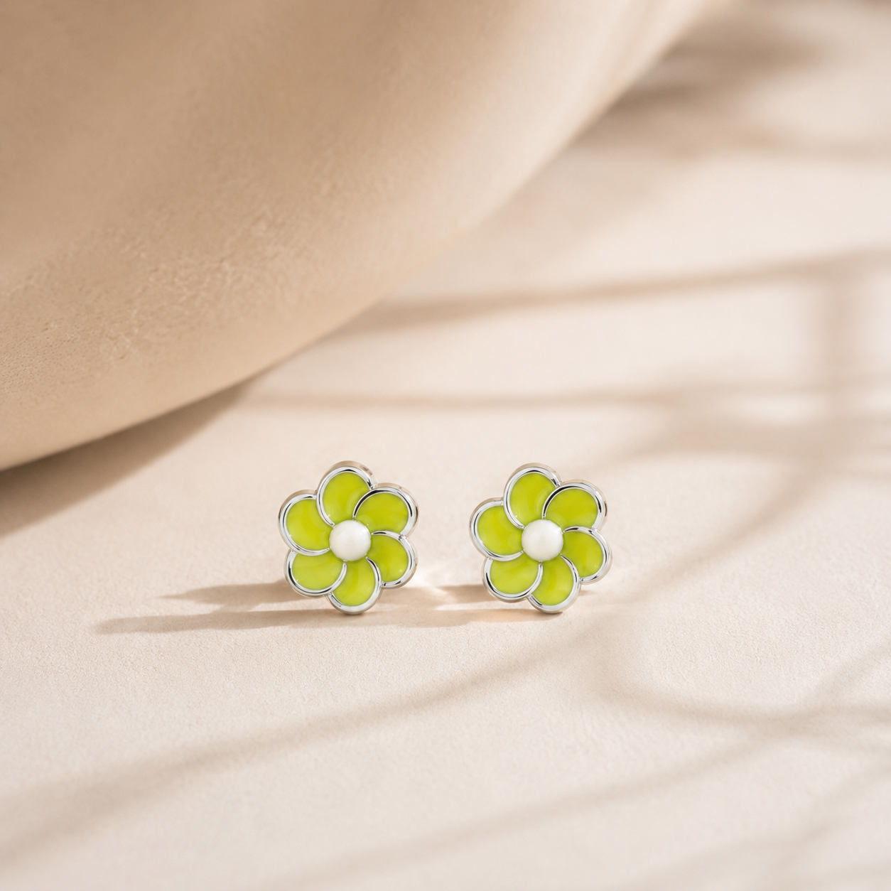 Lime Green Floral Enamel Silver Stud Earrings resting on a textured beige surface with soft shadows.