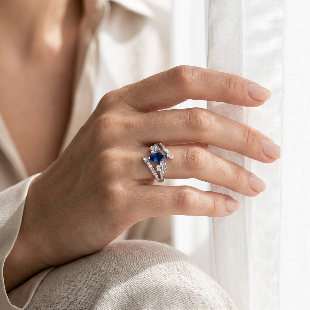 A woman's hand resting gracefully near a sheer white curtain wearing the Neelam Blossom Silver Bypass Ring.