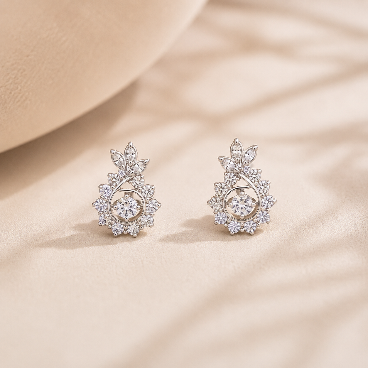 Close-up of Radiant Floral Swirl Silver Stud Earrings resting on a textured beige surface