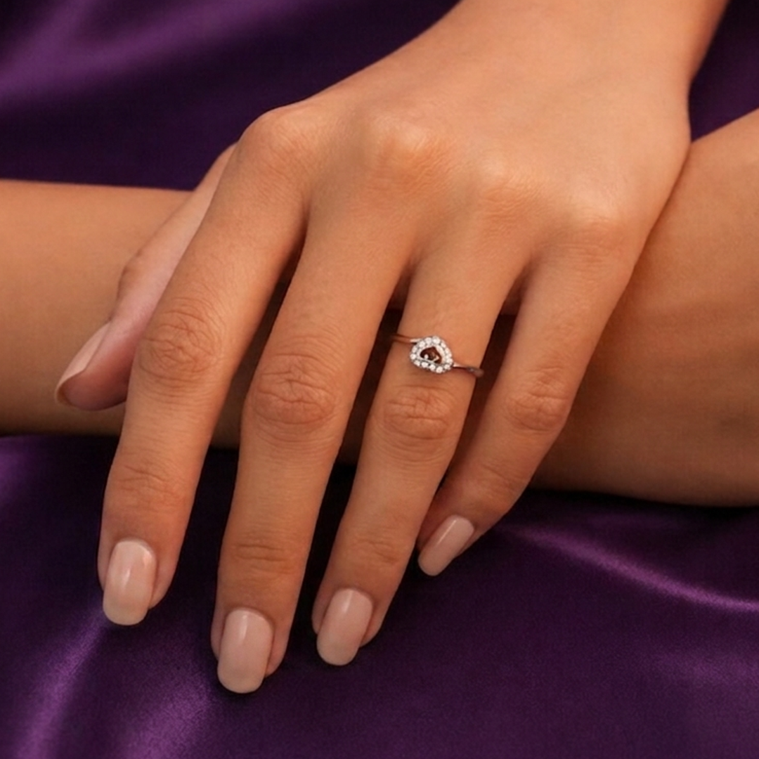 Close up of a woman's hands resting on purple silk fabric, wearing the stone-studded Radiant Open Heart Sterling Silver Ring.