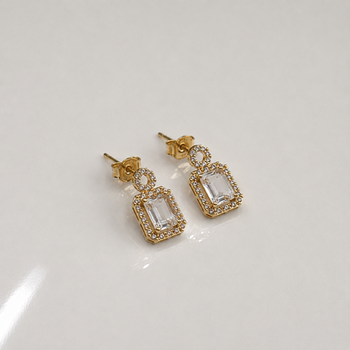 Angled view of Rose Gold Round Halo Emerald Cut Drop Earrings showing the round halo tops, emerald-cut stones and surrounding rectangular halos