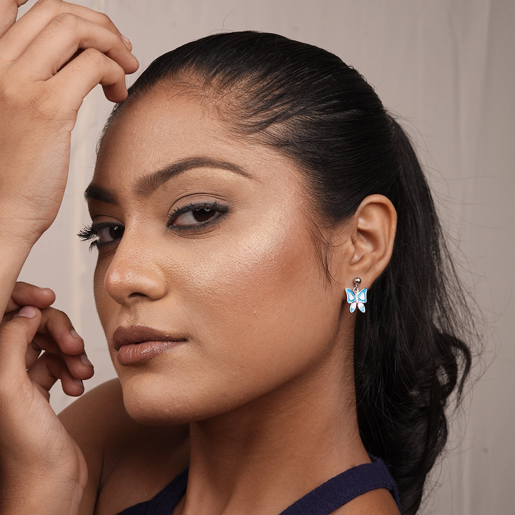 Model wearing Silver Blue and Pink Enamel Butterfly Drop Earrings with a colourful butterfly motif suspended below the round stud