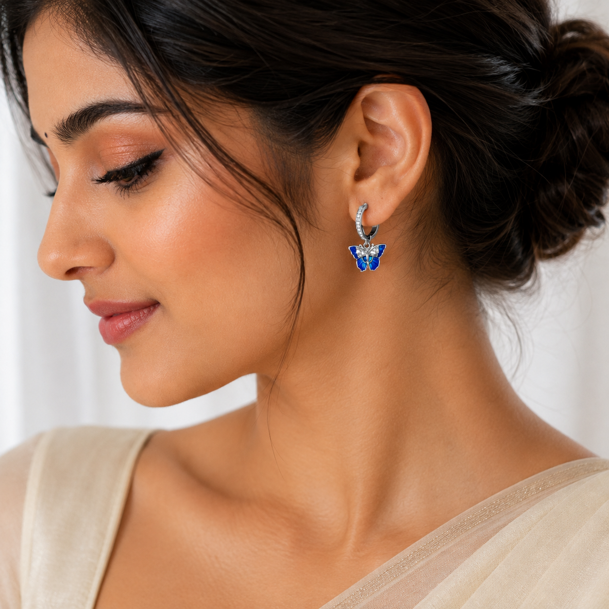 Model wearing Silver Blue Enamel CZ Butterfly Huggie Drop Earrings with dangling blue butterfly details