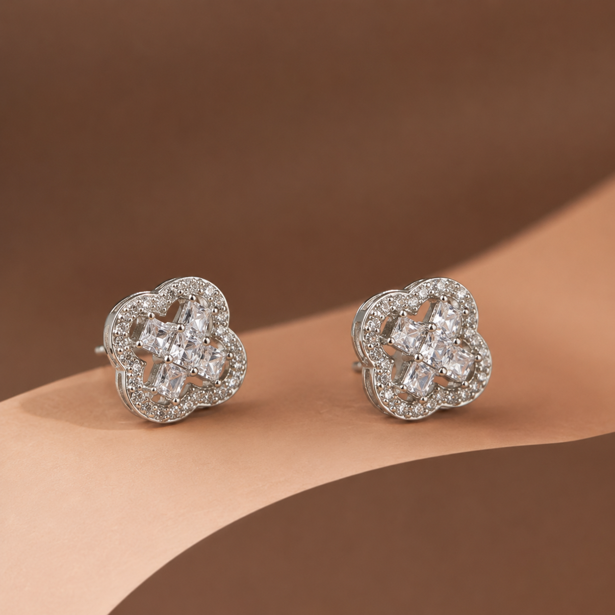 Pair of Silver Clover Stud Earrings (Princess Cut CZ) displayed at an angle, showing the princess-cut centre stones and pave outer frame
