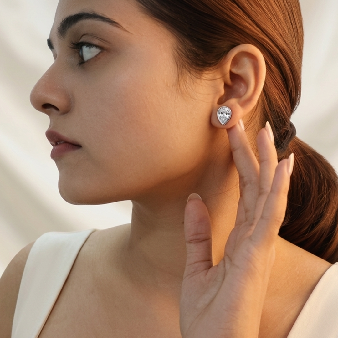 Close-up of a model wearing Silver Dainty Pear Cut Solitaire CZ Stud Earrings on the ear
